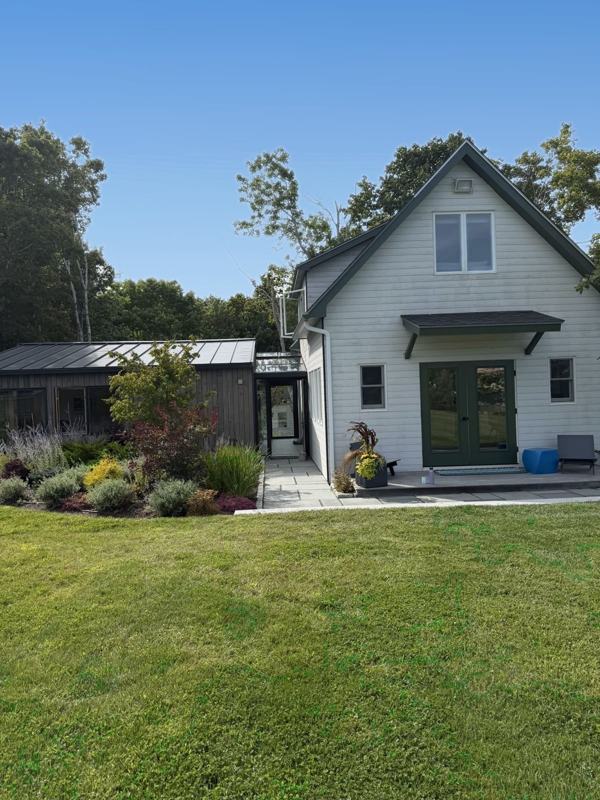 The Wreck House with green French doors, the glass breezeway and the Wreck Study beside a garden bed