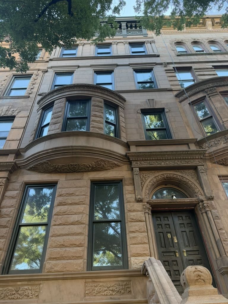 128 West 121st Street: carved brownstone facade with a rounded bay and arched doorway