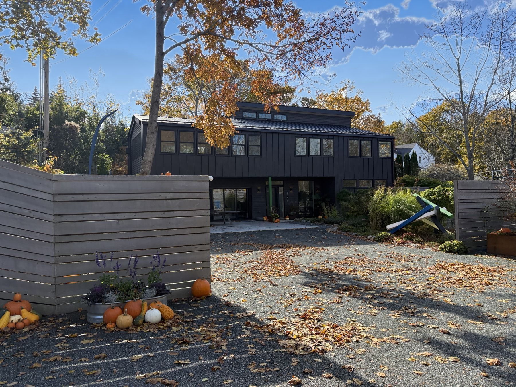 The Garage in autumn: black board-and-batten facade behind a gray slatted fence