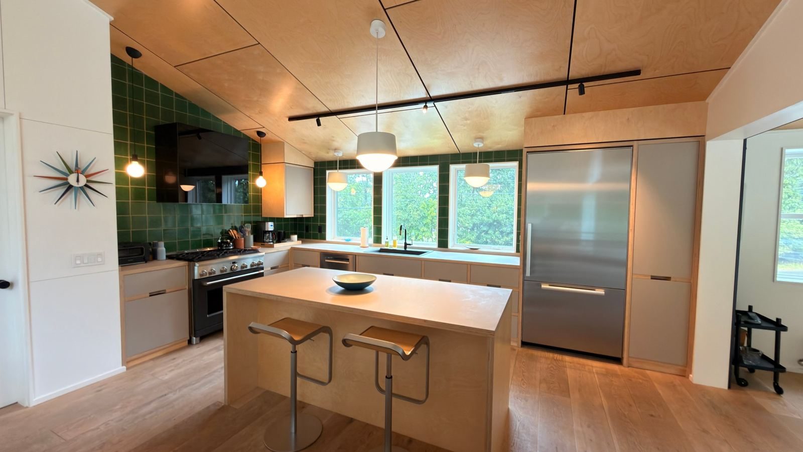 Kitchen with green tile and birch island