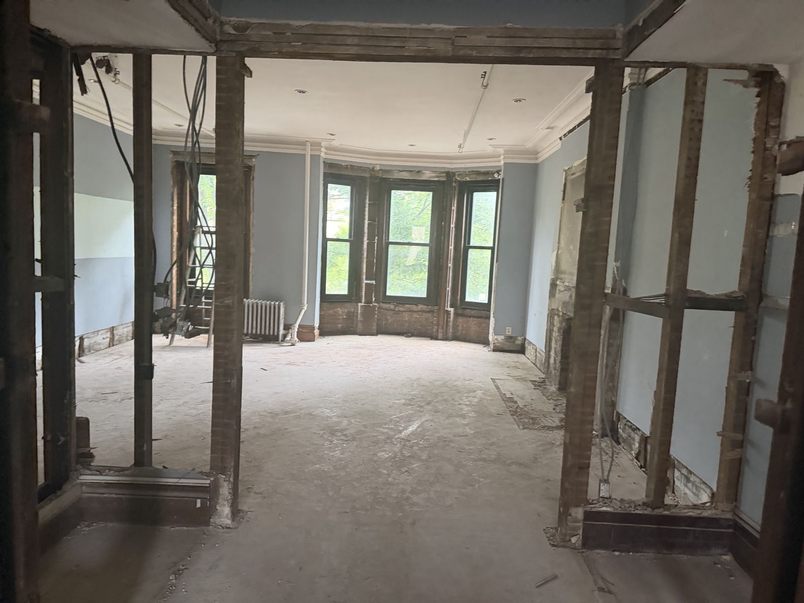 Parlor floor opened up for renovation, bay windows facing the trees