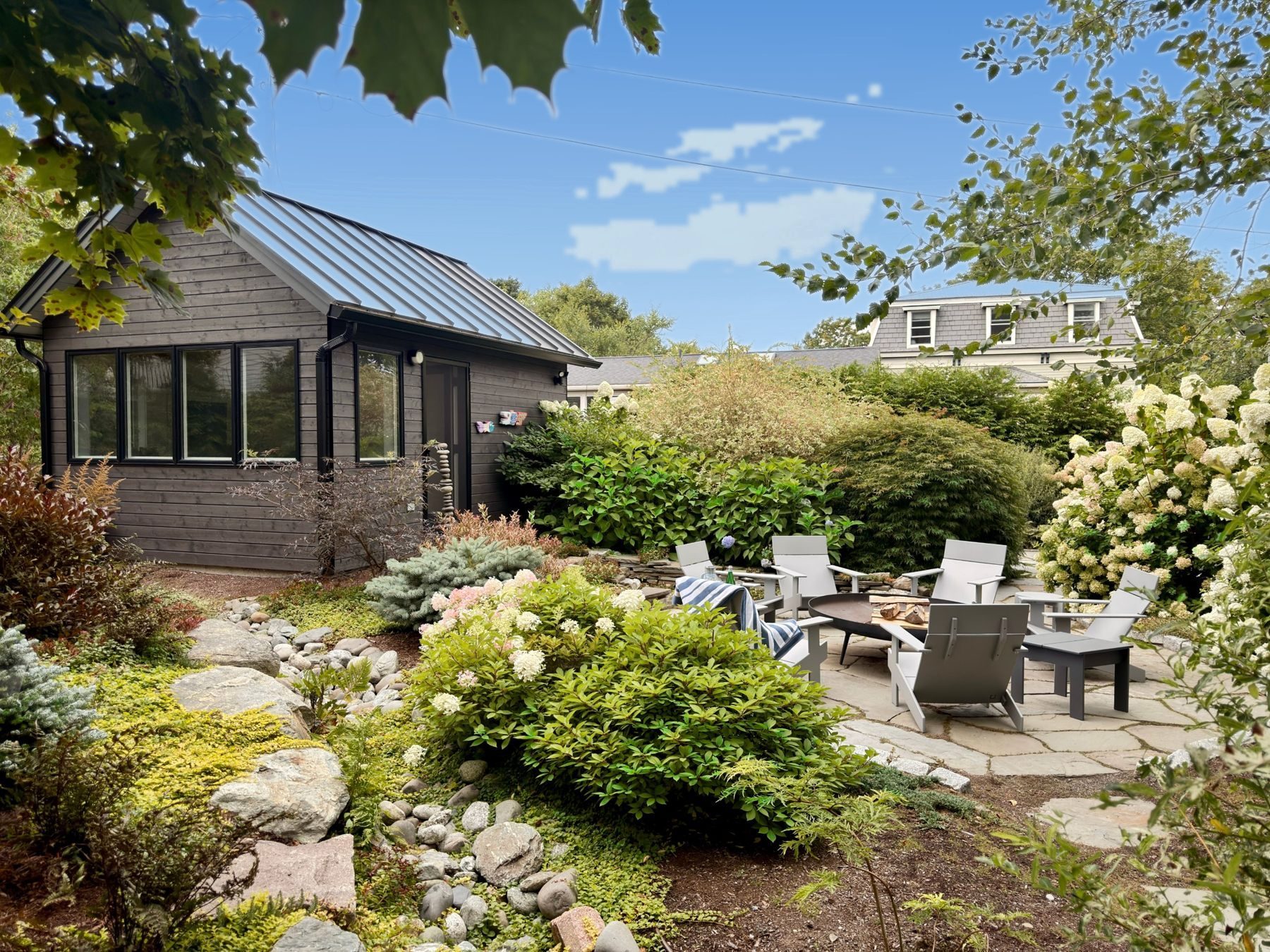 The Schoolhouse studio beside a stone fire-pit patio ringed by hydrangeas