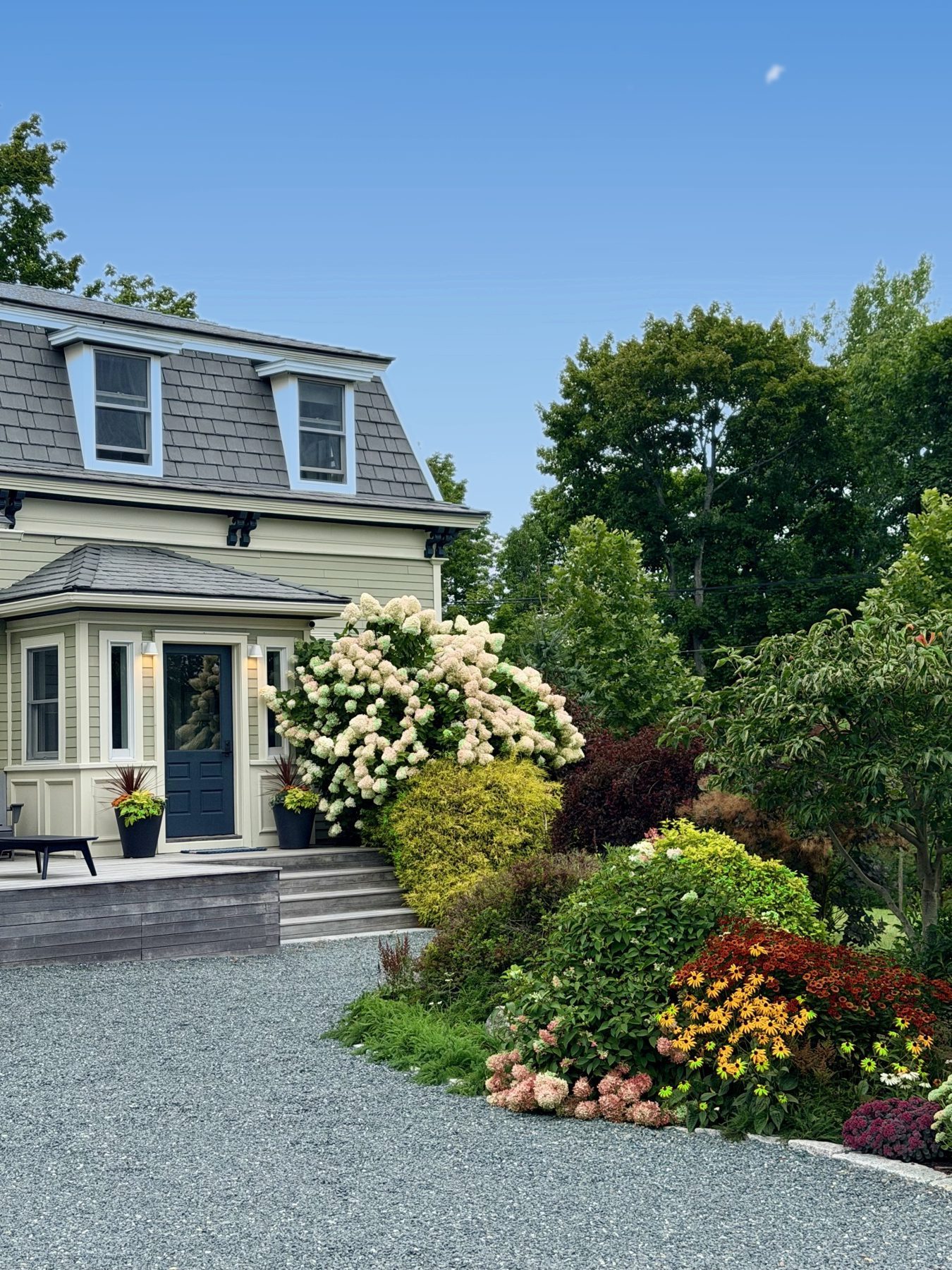 The Mansard's front porch framed by hydrangeas and a late-summer garden