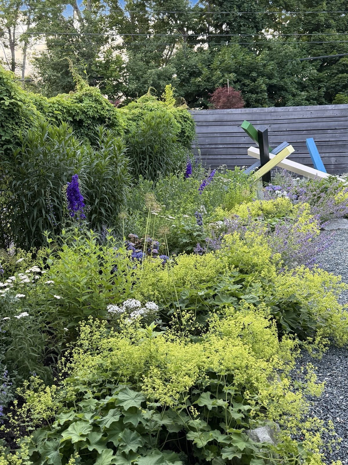 Lady's mantle and delphinium around a painted sculpture